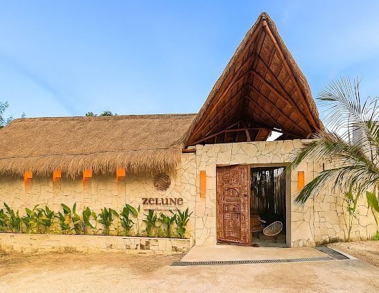 Exterior of Zellum, a building with thatched roof and wooden door, set against a blue sky.