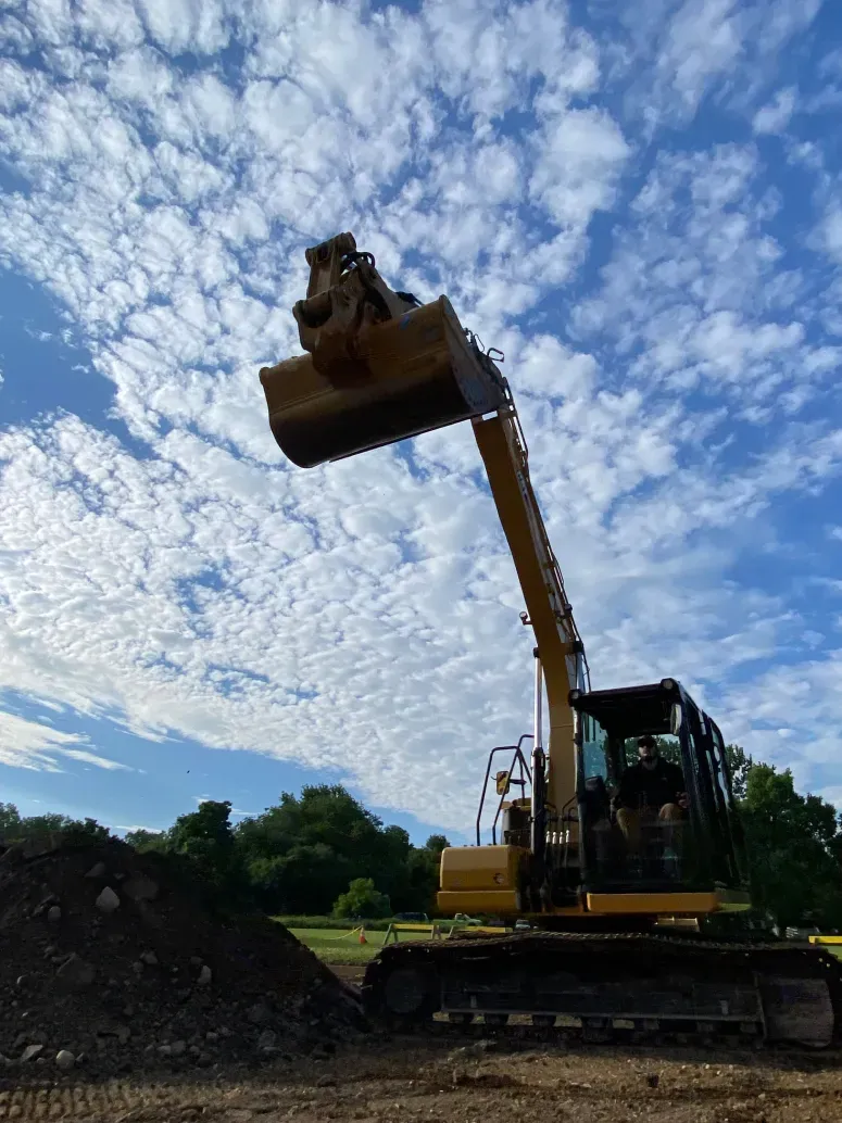 A bulldozer is moving dirt in a field with a blue sky in the background.