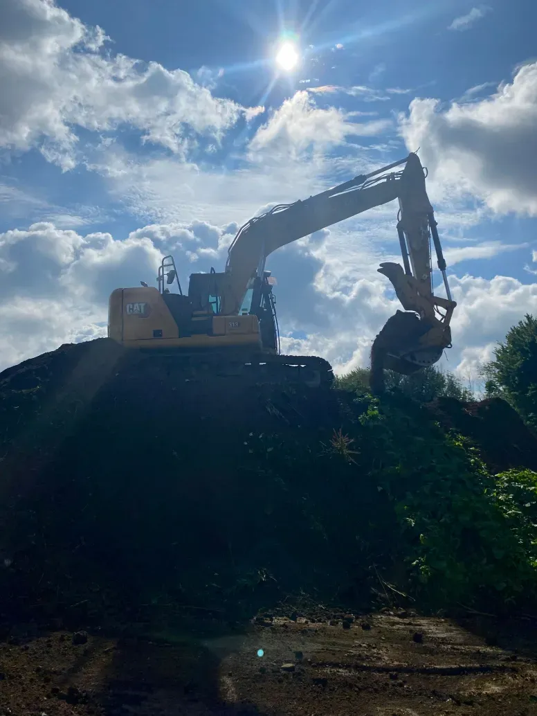 A large excavator is sitting on top of a pile of dirt.