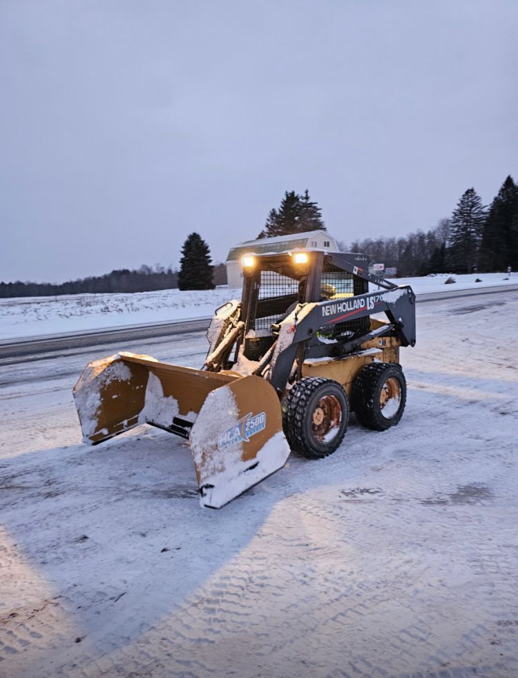 A snow plow is sitting in the snow on the side of the road.