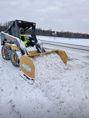 A man is driving a snow plow on a snowy road.