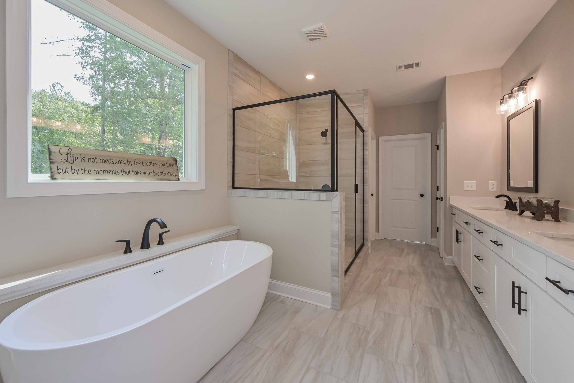 Modern bathroom with a white tub, shower, and double vanity; neutral tones, natural light.
