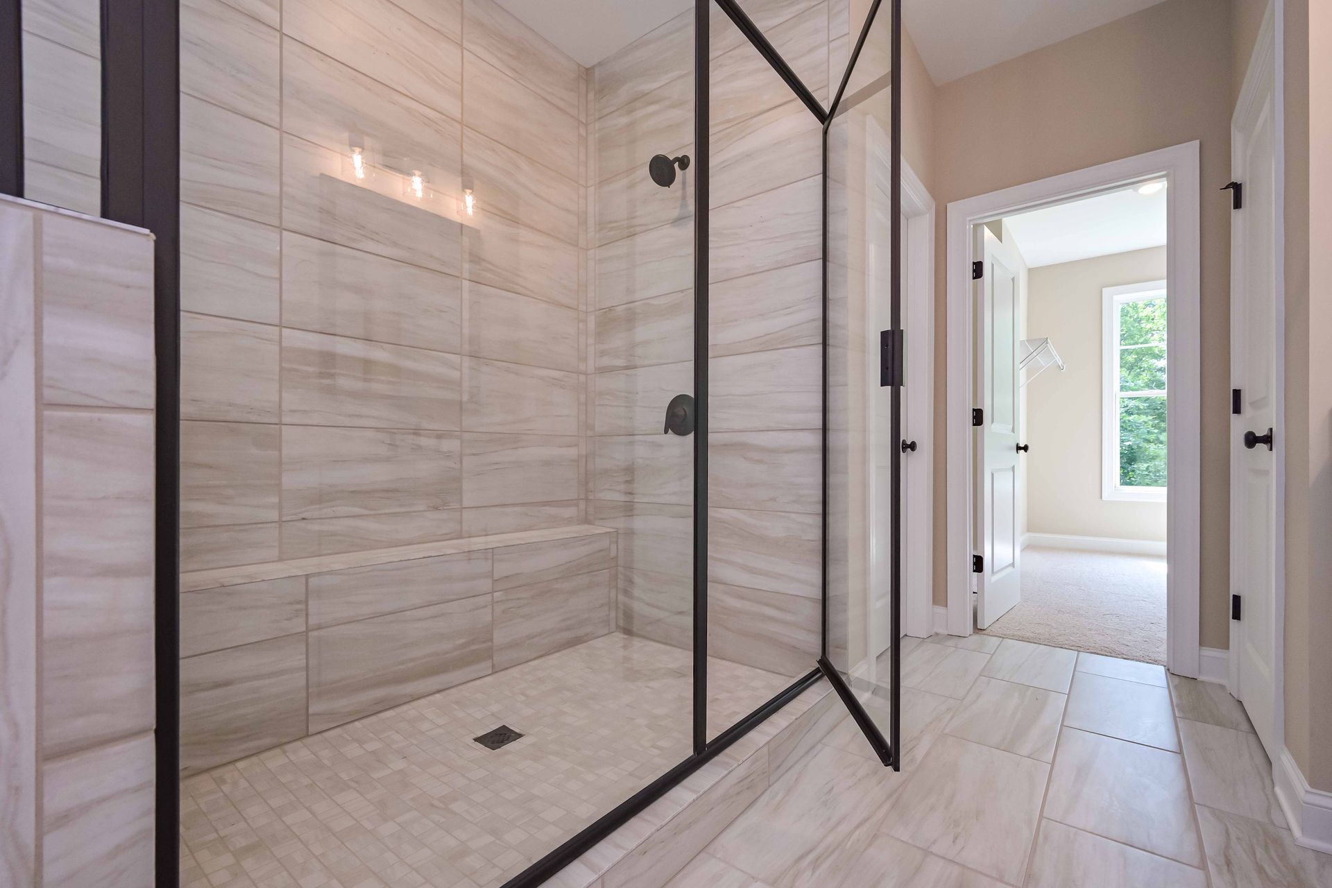 Modern bathroom with a glass shower enclosure and light-colored tile.