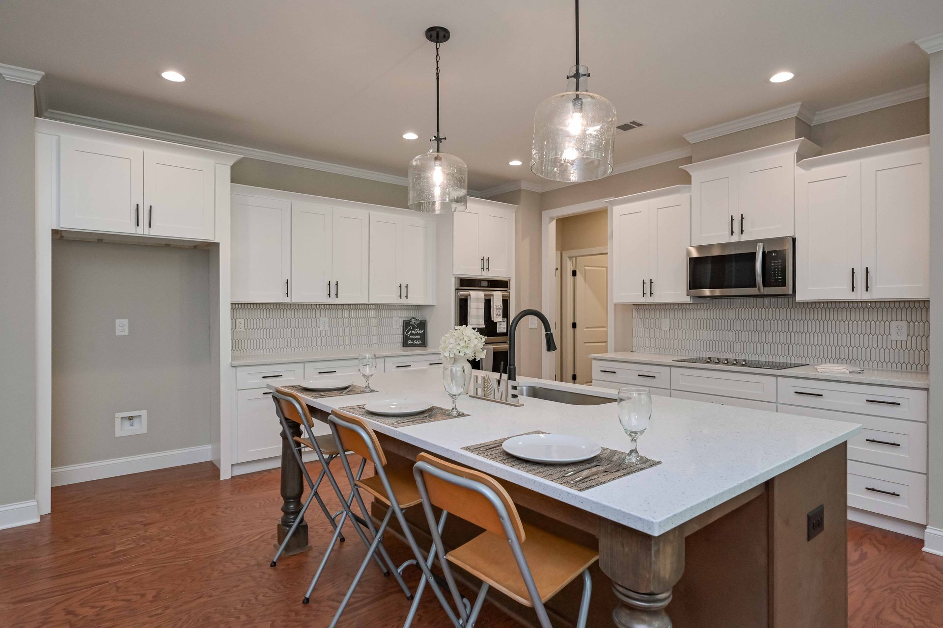 Modern kitchen with white cabinets, island with seating, and brown and orange flooring.