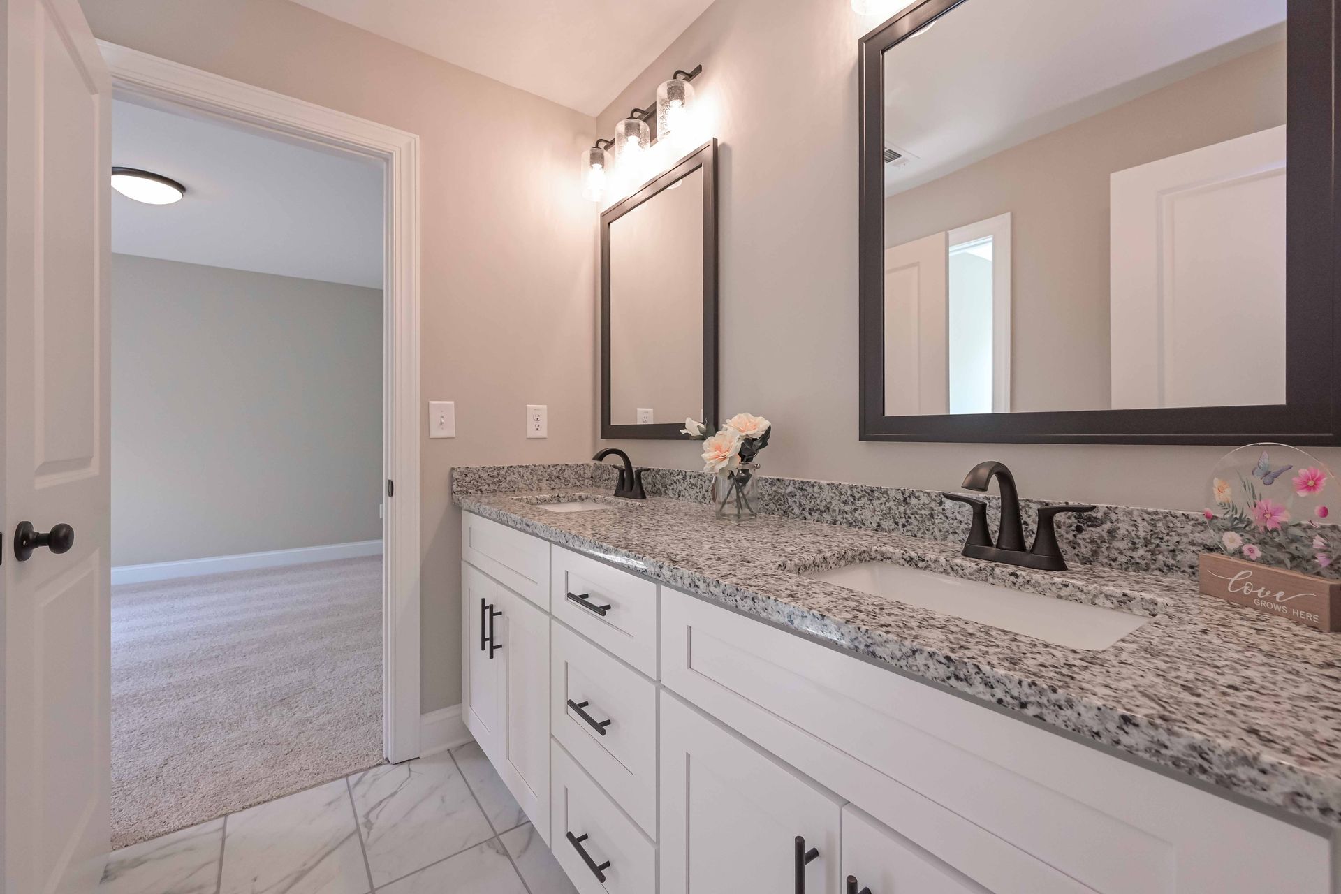 Bathroom with white cabinets, gray granite countertop, and black fixtures.