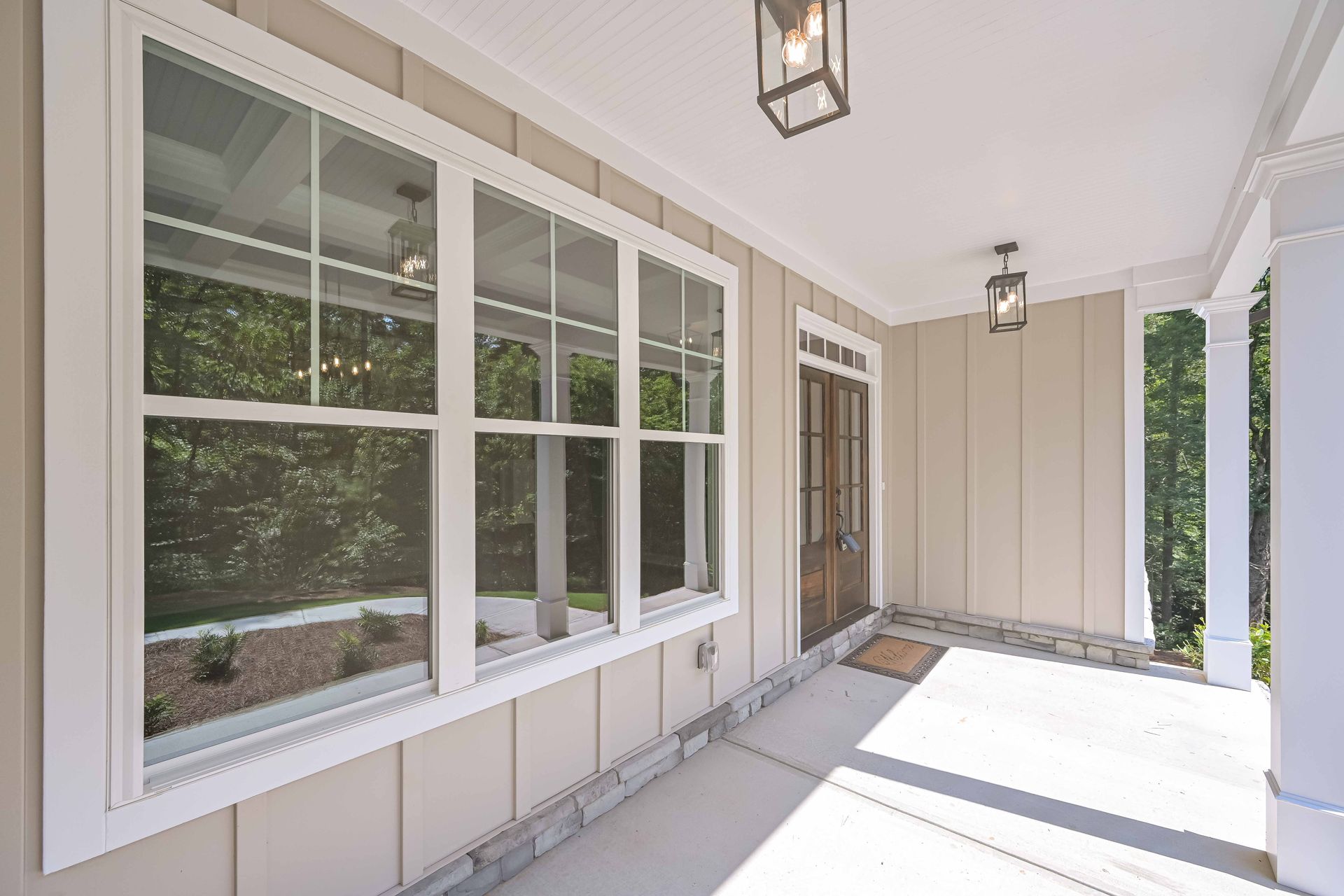 Covered porch with white trim, windows, and two hanging lights. Brown door is visible.
