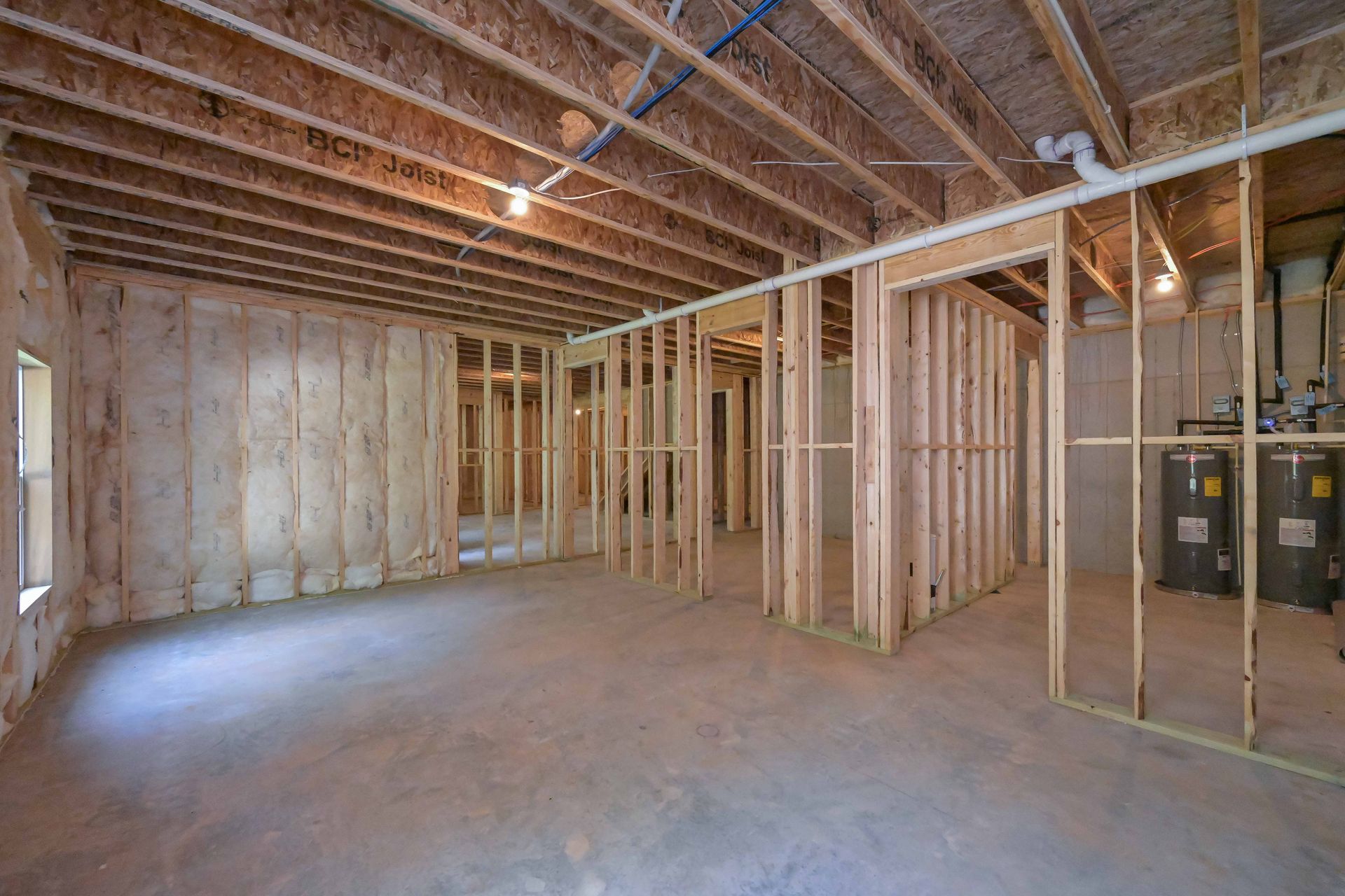 Unfinished basement with wooden framing, exposed ceiling joists, and concrete floor.
