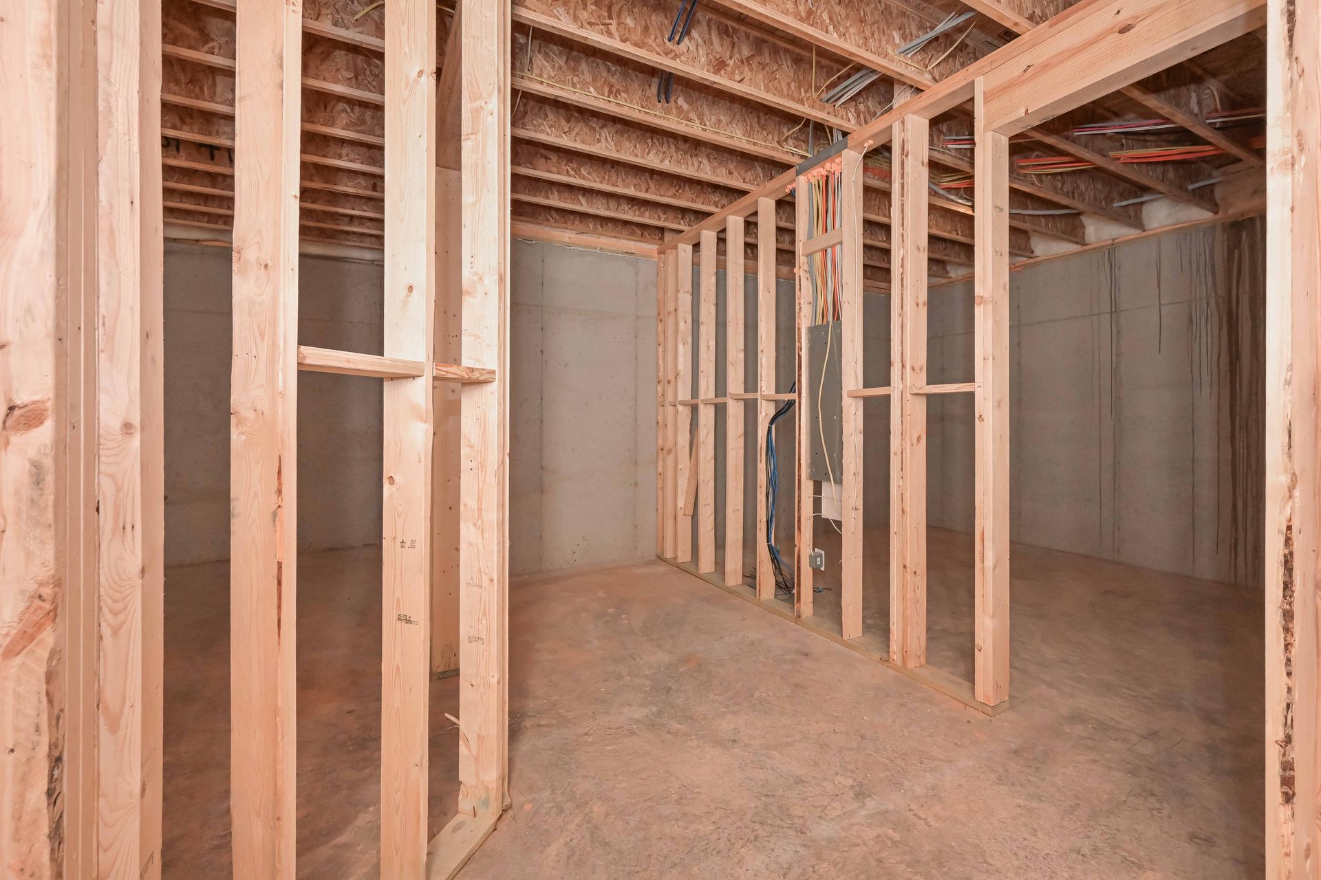 Interior view of a basement under construction with wooden framing and concrete walls.