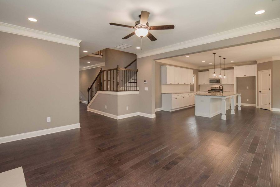 Open-concept living space with hardwood floors, kitchen, and staircase.