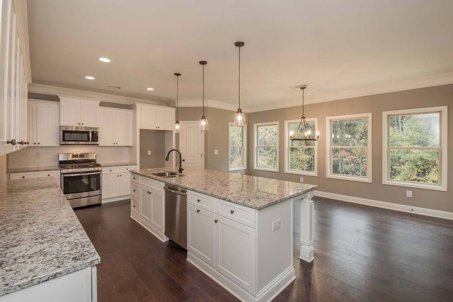 Modern kitchen with white cabinets, stainless steel appliances, granite countertops, and a large island.