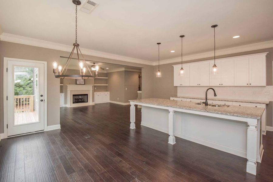 Spacious kitchen with dark wood floors, white cabinets, and an island.