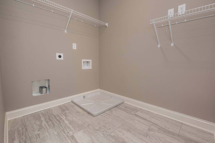 Empty laundry room with gray walls, white shelves, and gray tiled floor.