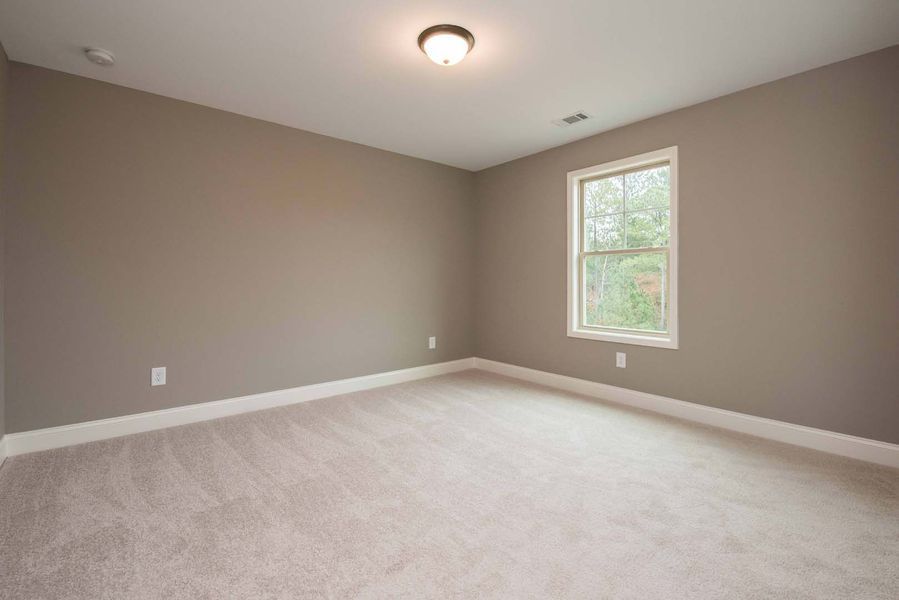 Empty room with beige walls, white trim, window, carpet, and light fixture.