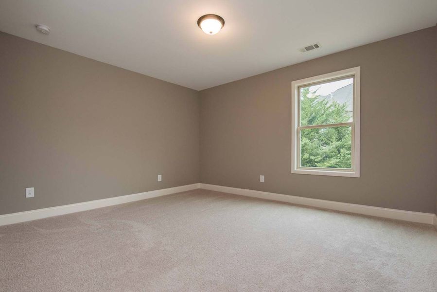Empty room with beige walls, carpet, and window.