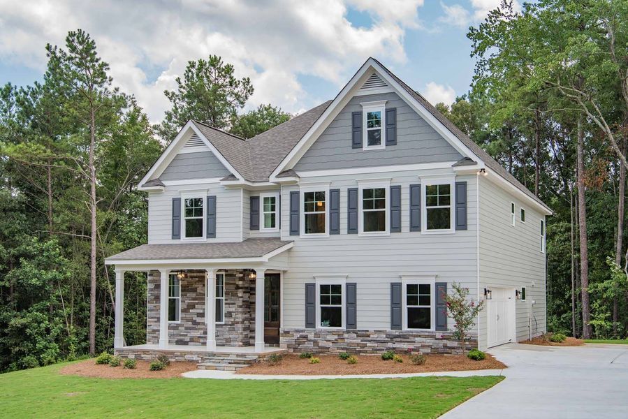 Two-story white house with gray accents and dark blue shutters, surrounded by trees and a driveway.