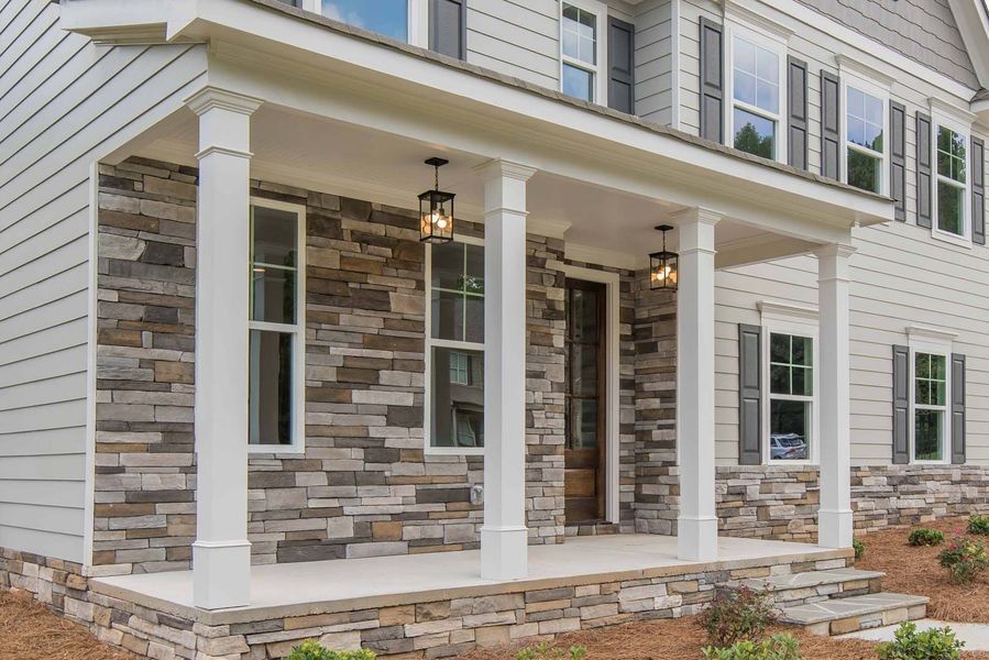 Two-story house with a stone facade porch, white columns, and windows with dark shutters.