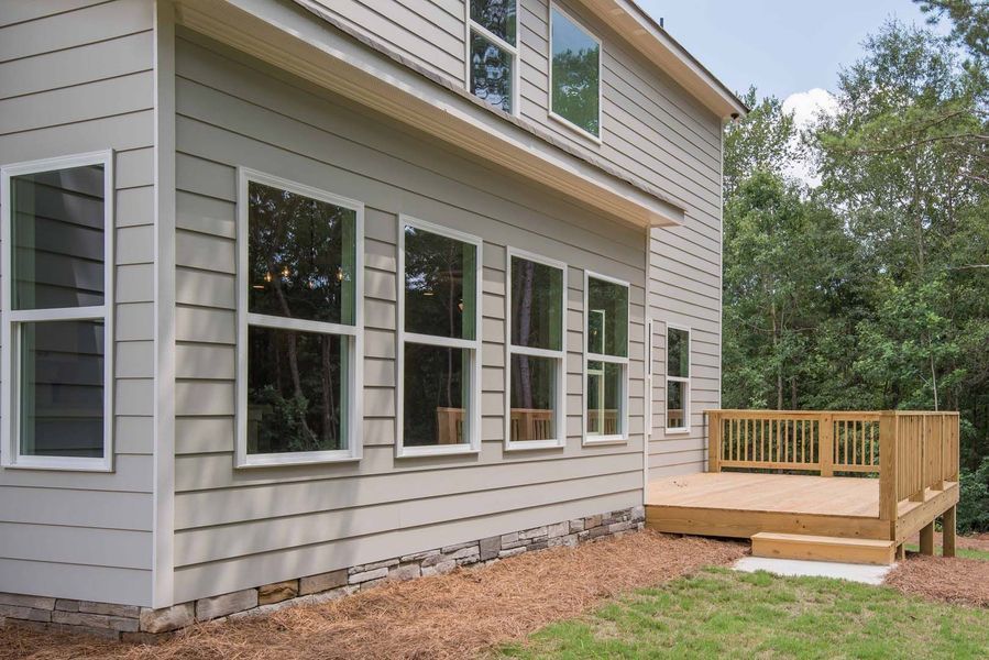 Light gray house exterior with multiple windows and a wooden deck.