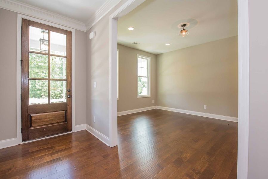Wooden door with glass panels and a room with hardwood floors.