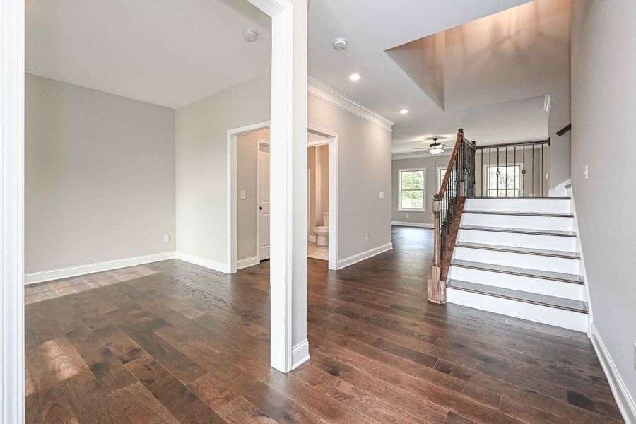 Entryway with dark wood floors, stairs, and a white column.