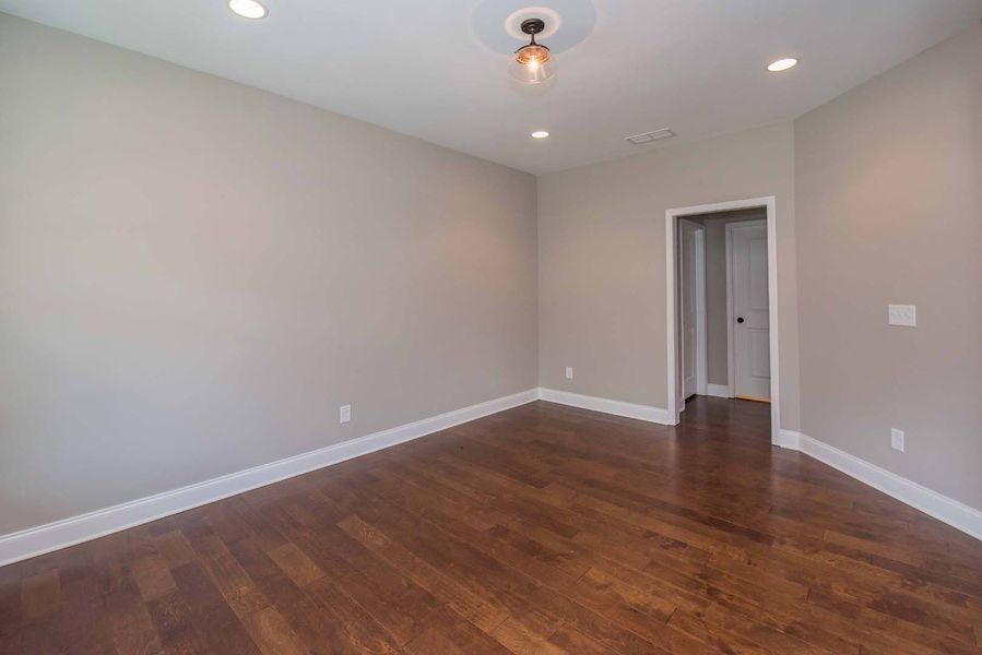 Empty room with dark wood floor, neutral walls, white trim, and door.