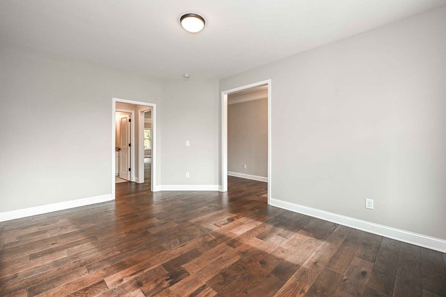 Empty room with hardwood floors, gray walls, and two doorways.