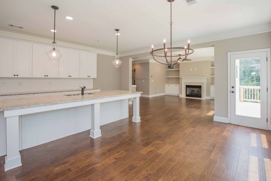 Modern kitchen and living room with white cabinets, island, fireplace, and hardwood floors.