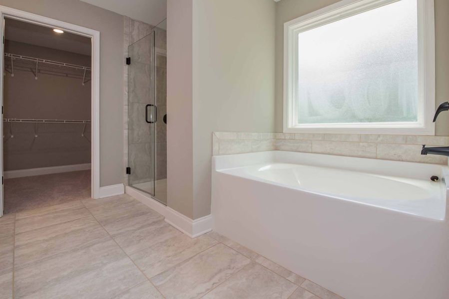 Modern bathroom with a white tub, glass shower, and a walk-in closet.