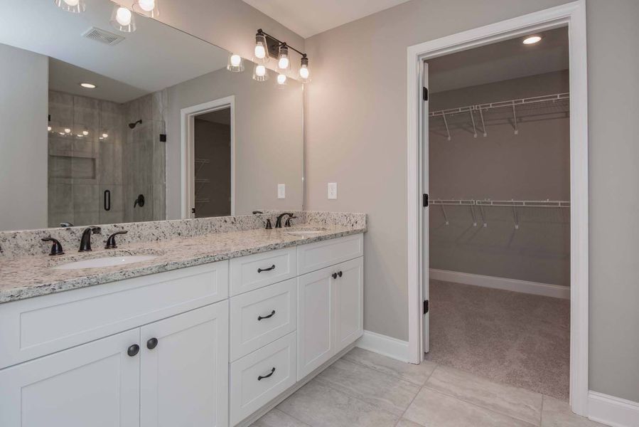Bathroom with white cabinets, granite countertop, and a walk-in closet.