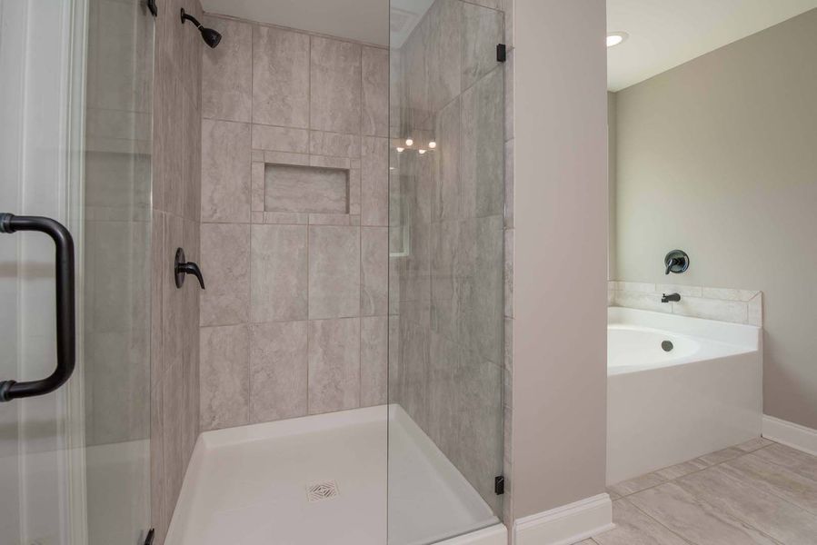 Modern bathroom with a glass shower, tile walls, and a built-in bathtub.