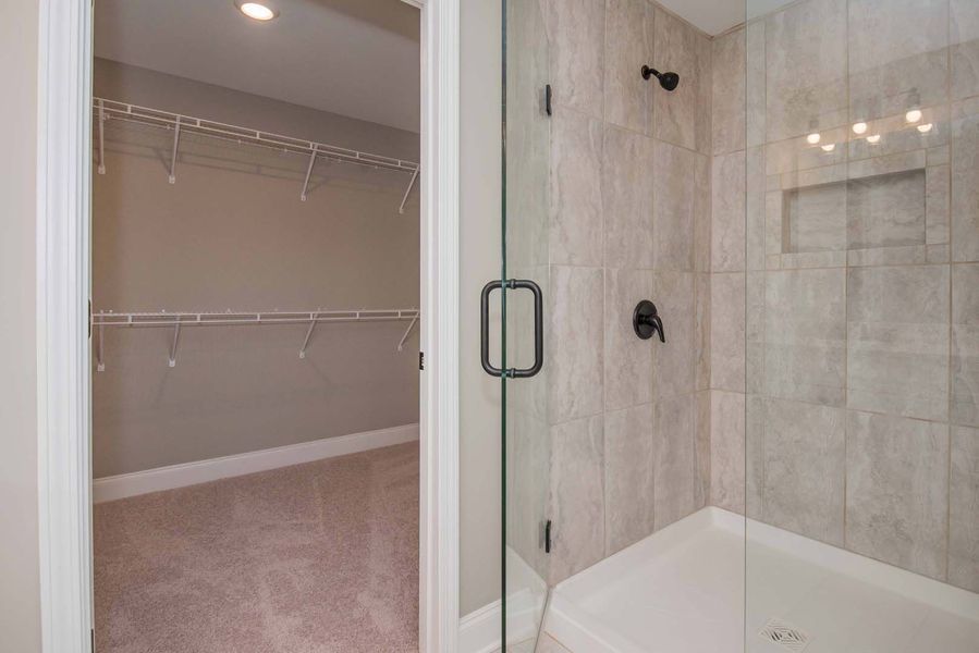 Bathroom with glass shower and walk-in closet. Neutral colors, modern fixtures.