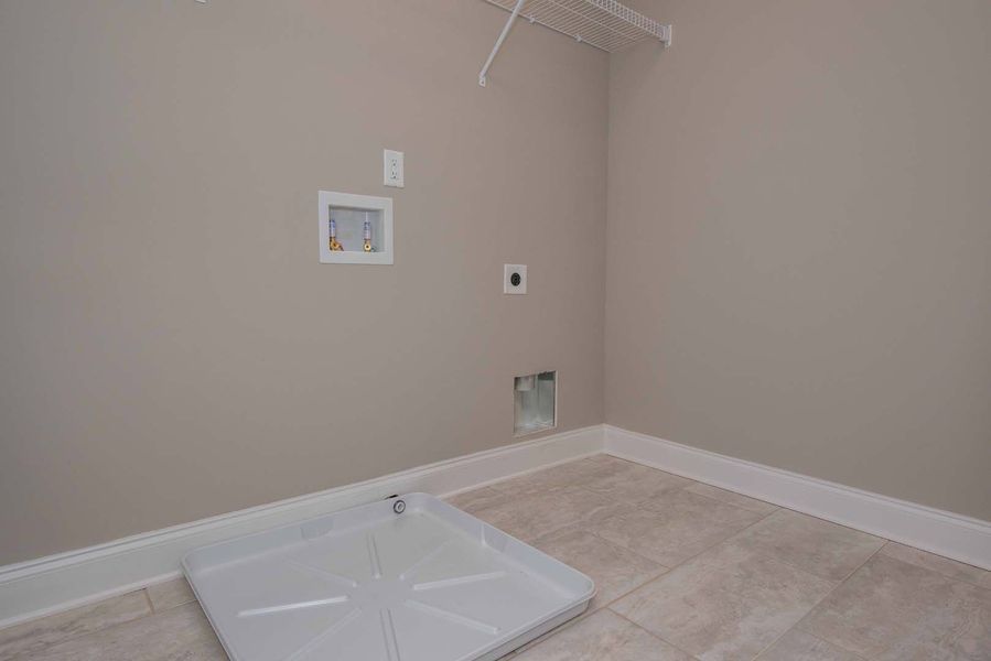 Empty laundry room with tan walls, white trim, and a floor drain.