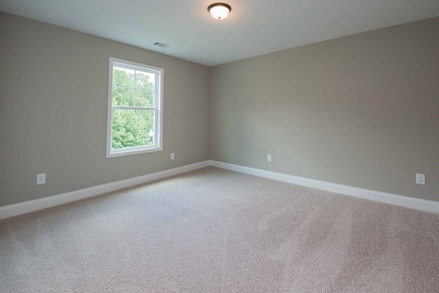 Empty room with beige walls, carpet, and a window.