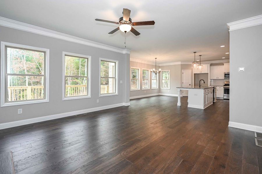 Spacious living room with dark wood floors, light gray walls, and a view of the kitchen.