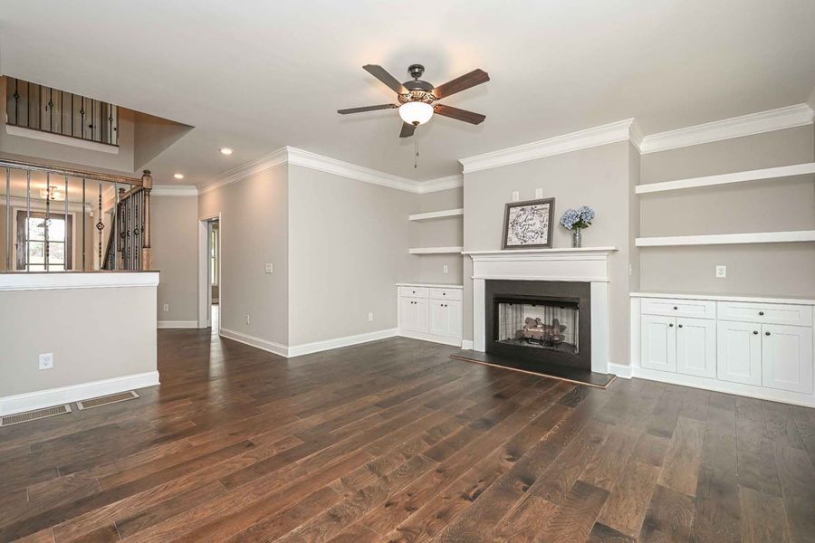 Living room with hardwood floors, fireplace, built-in shelves, and ceiling fan.