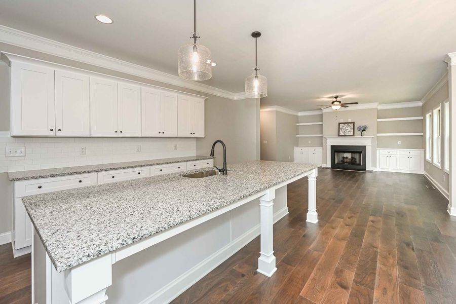 Modern kitchen with white cabinets, gray countertops, and hardwood floors.