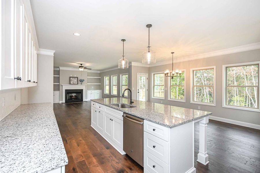 Kitchen with granite countertops, white cabinets, island with sink and stainless steel dishwasher, and dark hardwood floors.