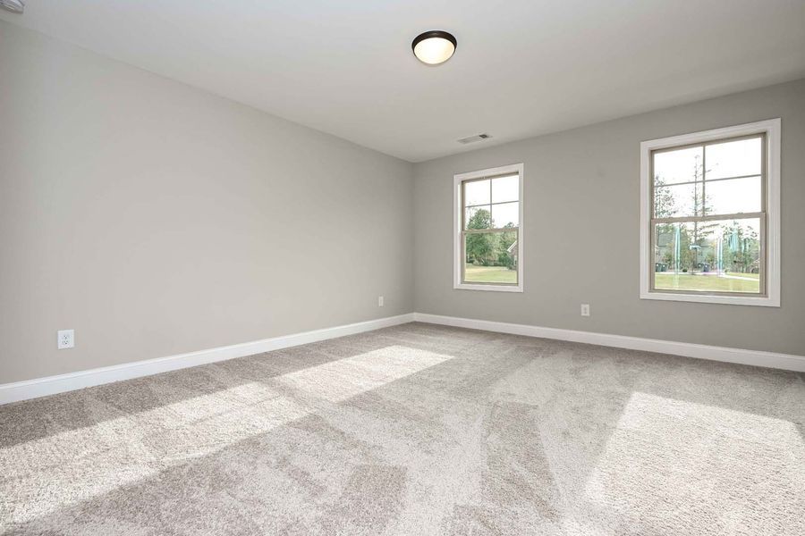 Empty bedroom with gray walls, carpet, and two windows.