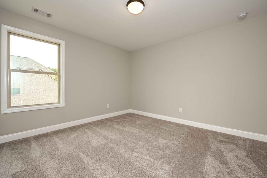 Empty room with gray walls, carpet, window, and ceiling light.