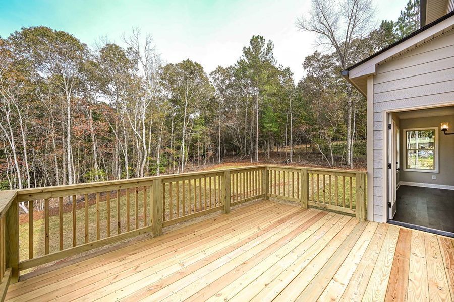 Wooden deck overlooking a wooded area, connected to a light-colored house.