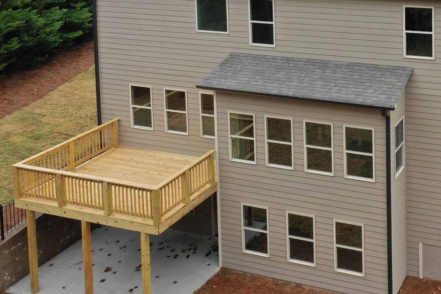 Wooden deck and attached sunroom on the back of a house with tan siding.