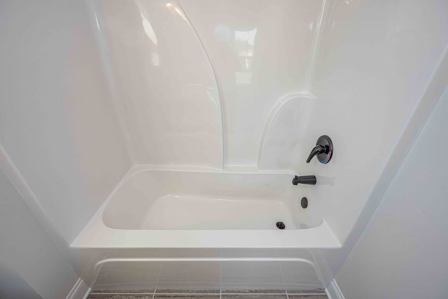 White bathtub with black faucet and showerhead.