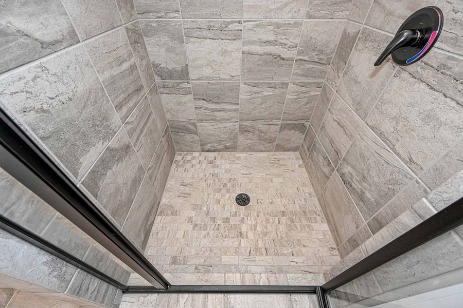 Gray tiled shower with black-framed glass doors.