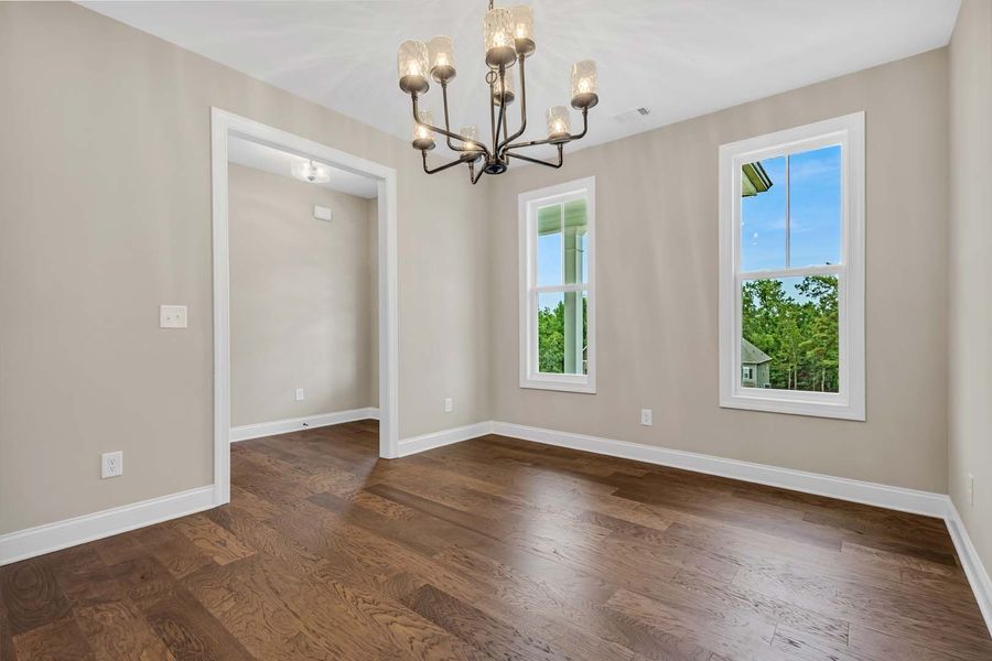Dining room with hardwood floors, light gray walls, white trim, windows, and a chandelier.