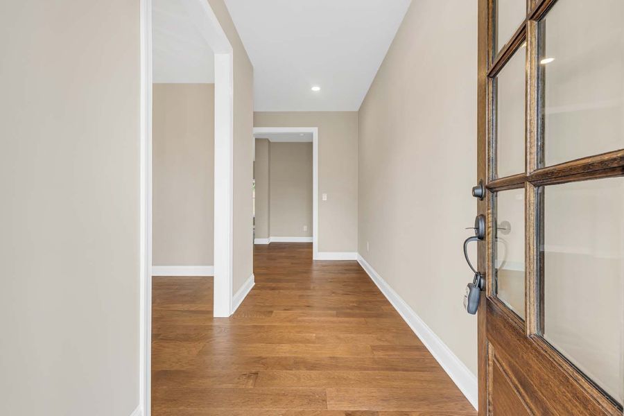 Entryway with hardwood floor, light walls, and open doorways. A wooden door is partially open.