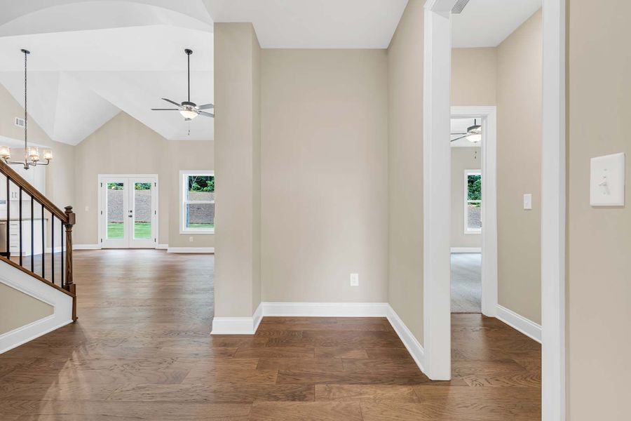 Interior view of a home with wooden floors, beige walls, and a staircase leading to a living area.