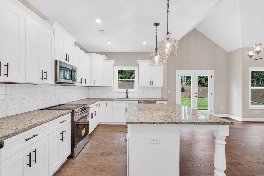 White kitchen with granite countertops, stainless steel appliances, and island.