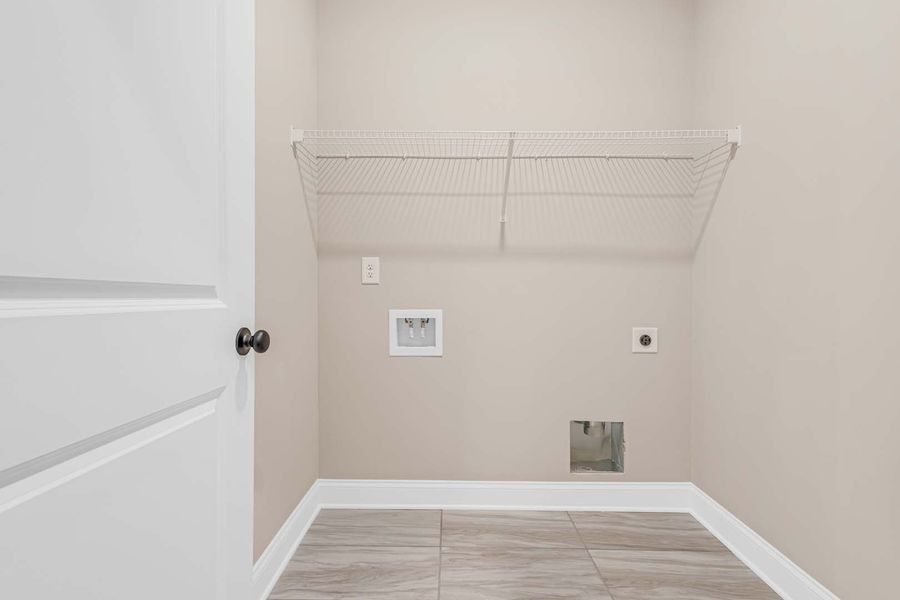 Empty laundry room with white walls, wire shelf, and tiled floor.
