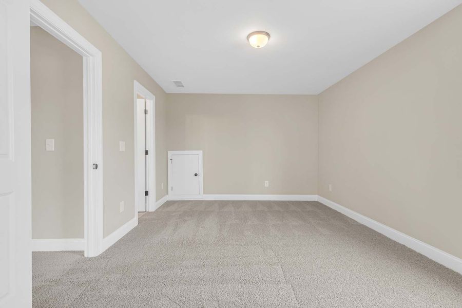 Empty room with carpet, beige walls, white trim, and two doorways.