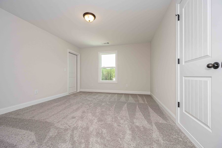 Empty room with gray carpet, white walls, door, and window.