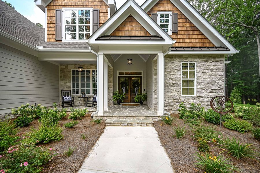 Stone facade house with a front porch, walkway, and landscaped yard.
